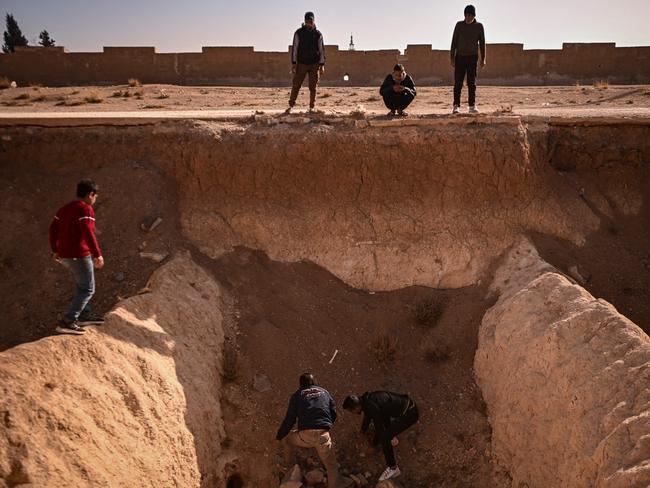 TOPSHOT - People search for human remains at a trench believed to be used as a mass grave on the outskirts of Damascus on December 16, 2024. Islamist-led rebels took Damascus in a lightning offensive on December 8, ousting president Bashar al-Assad and ending five decades of Baath rule in Syria. According to the Syrian Observatory for Human Rights, more than 100,000 people died in Syria's jails and detention centres from 2011. (Photo by Aris MESSINIS / AFP)