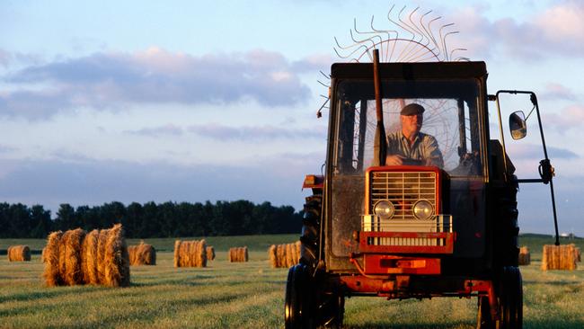 Farmer Driving Tractor in a Field at sunrise. Thinkstock