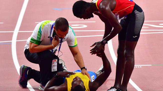 Jonathan Busby collapses after crossing the finish line in the 5000m heats.