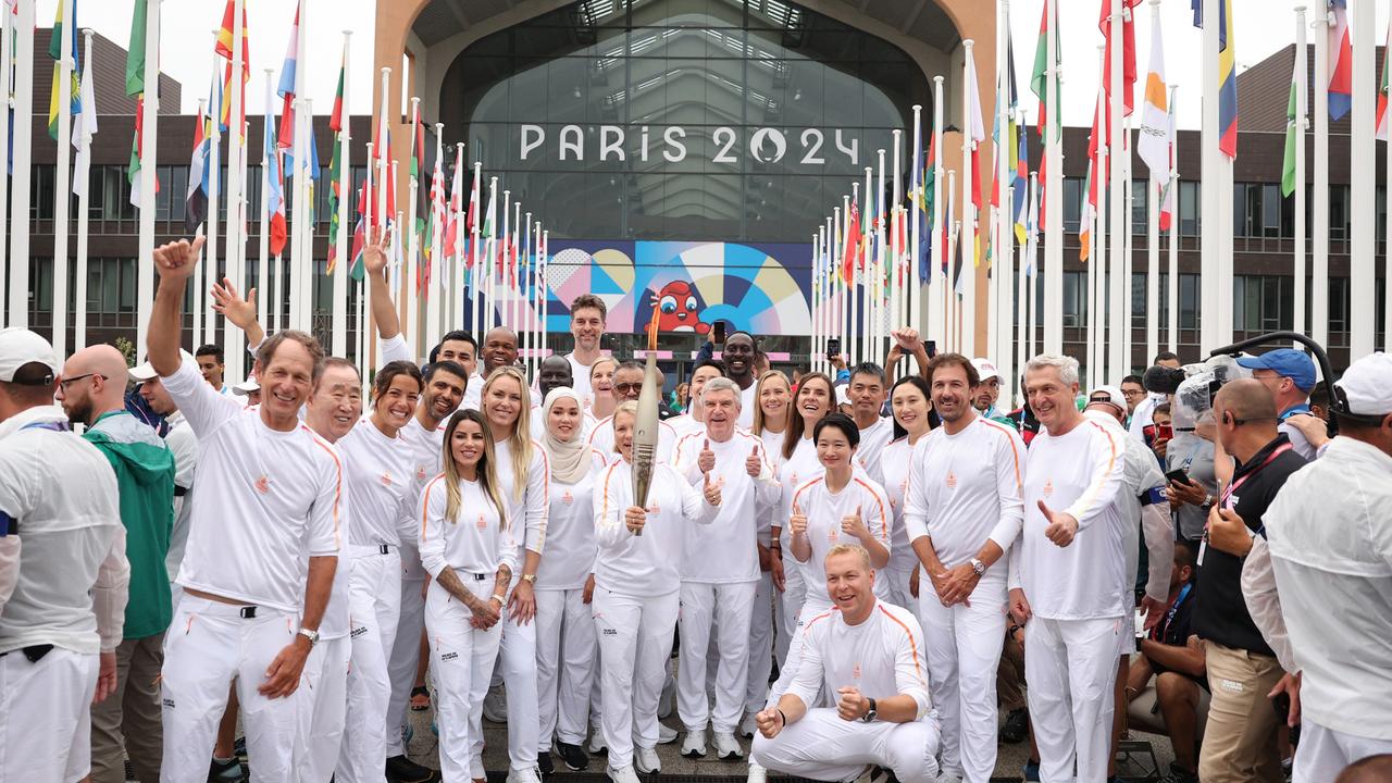 Torchbearers pose for group photos during the Olympic Village torch relay in the Olympic Village. Picture: Jia Haocheng - Pool/Getty Images