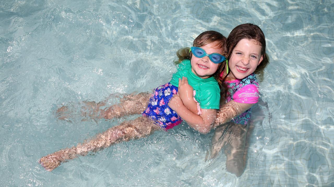 Sisters Emily and Lucy Bourke played happily in the cool water of Marion Outdoor Pool. Picture: AAP/Emma Brasier