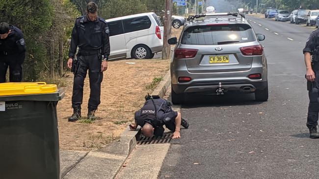 Police search a drain on Govetts Leap Rd, Blackheath, in the aftermath of last week's double shooting.