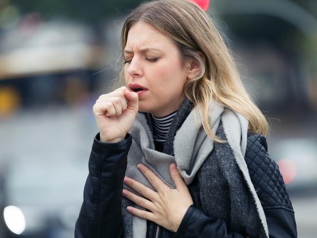 Shot of illness young woman coughing in the street.