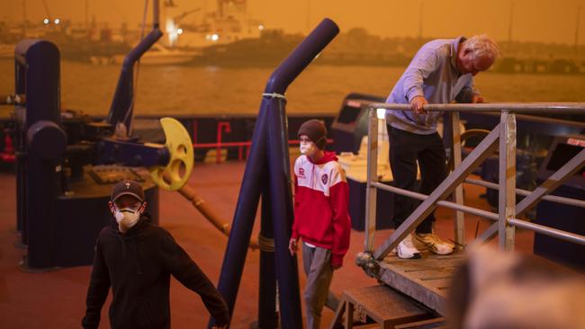 People board one of two tug boats at Eden Wharf at Snug Cove on Sunday. Pic: Sean Davey.