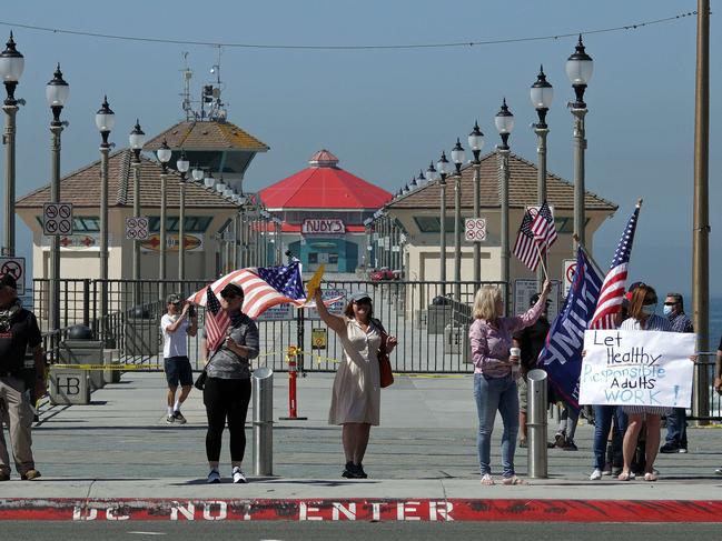 People protesting the statewide stay at home order stand in front of the Huntington Beach pier. Picture: AFP