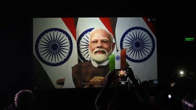 People watch as India's Prime Minister Narendra Modi congratulates the Indian Space Research Organisation (ISRO) for the successful lunar landing of Chandrayaan-3 spacecraft on the south pole of the moon. (Photo by Dibyangshu SARKAR / AFP)