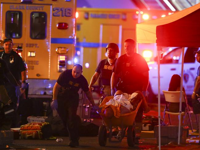 A wounded person is walked in on a wheelbarrow by police. Picture: Chase Stevens/Las Vegas Review-Journal via AP)