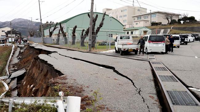 People stand next to large cracks in the pavement after evacuating into a street in the city of Wajima, Ishikawa prefecture after a major 7.5 magnitude earthquake. Picture: AFP