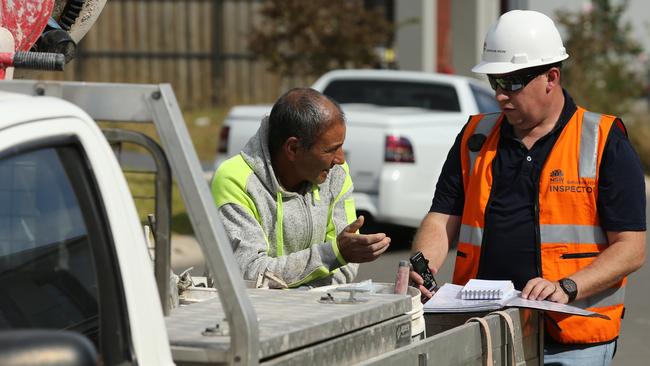 A SafeWork inspector speaks to a builder outside the construction site. Picture: Tim Hunter