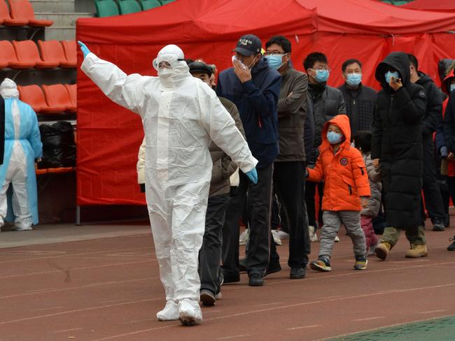 A worker wearing a protective suit leads residents to a makeshift Covid-19 testing centre in Tianjin after new coronavirus cases were detected in the city. Picture: AFP / China OUT