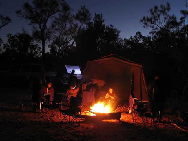 Relaxing by camp fire with silouetted trees