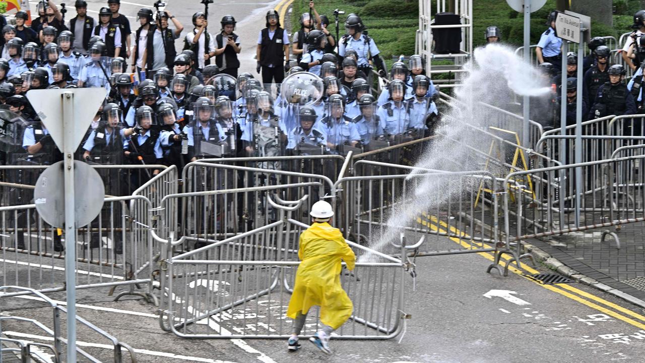 Police officers use a water canon on a lone protester near the government headquarters. Picture: Anthony Wallace/AFP