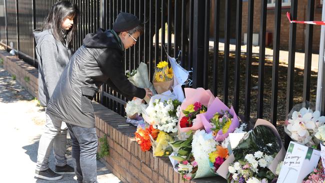 People laying flowers at the scene of a car crash outside Hurstville Public School, where a 12 year old boy died yesterday morning.