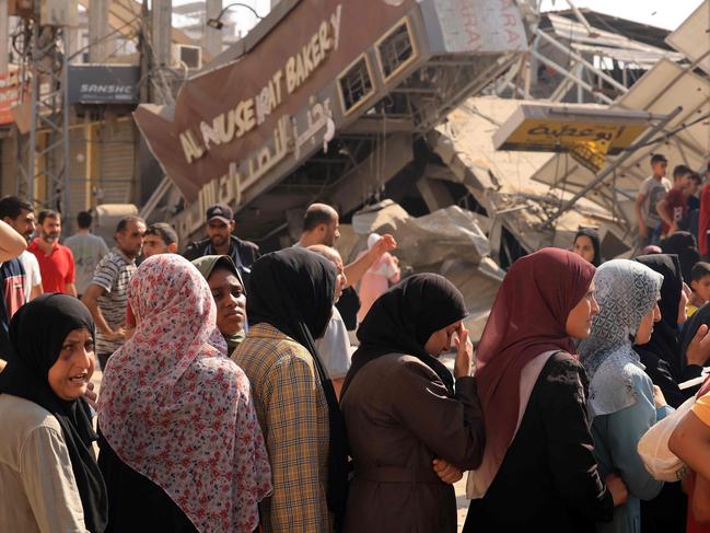 People queue for bread in front of a bakery that was partially destroyed in an Israeli strike, in the Nuseirat refugee camp in the central Gaza Strip. Picture: AFP