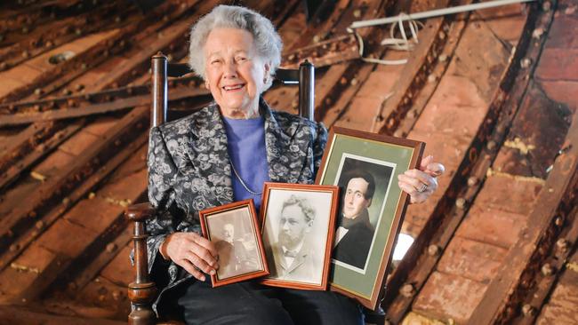 Pam Whittle sits in front of the captain's quarters of the City of Adelaide clipper ship with photos of her great-grandfather David Bruce and two other captains, his sons John and Alexander Bruce. Picture:AAP/Morgan Sette