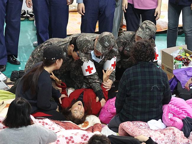 Getting help ... army doctors attend one of parents whose children were aboard the Sewol ferry and are now missing, on the floor at a gymnasium in Jindo. Picture: Ahn Young-joon