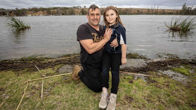 Paisley residents Adam Barnhardand his daughter Tatum in front of their Paisley home as the Murray waters slowly increase in volume. Picture: Emma Brasier