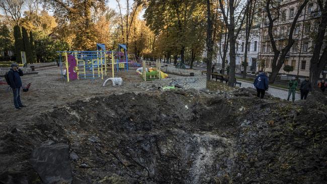 People inspect a crater left by a missile strike on October 11 in a playground in Taras Shevchenko Park in Kyiv. Picture: Getty Images