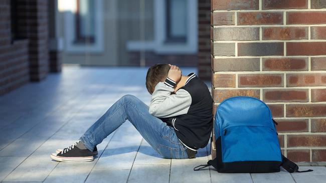 A schoolboy crying in the hallway of the school.