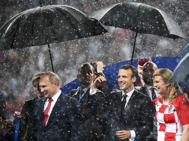 Russian President Vladimir Putin (L), French President Emmanuel Macron (C) and Croatian President Kolinda Grabar-Kitarovic stand in the rain during the trophy ceremony.