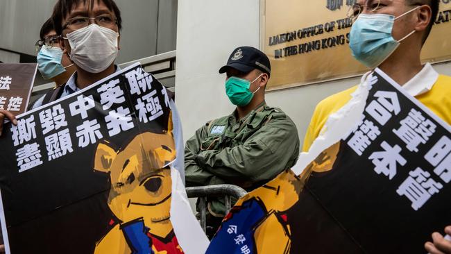 Pro-democracy activists tear a placard of Winnie-the-pooh that represents Chinese President Xi Jinping, during a protest against a proposed new security law outside the Chinese Liaison Office in Hong Kong. Picture: AFP