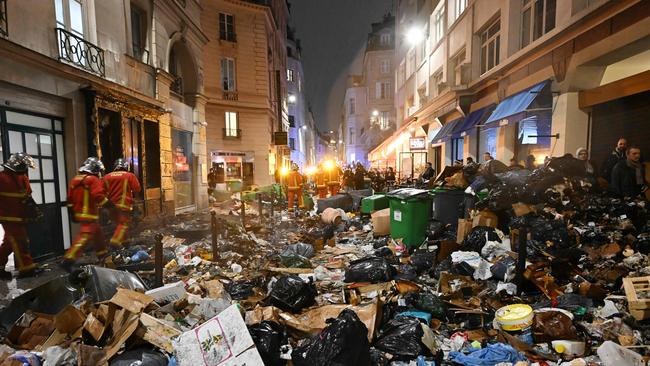 Firefighters check rubbish after extinguishing a fire during a demonstration, a week after the government pushed a pensions reform through French parliament without a vote. Picture: AFP