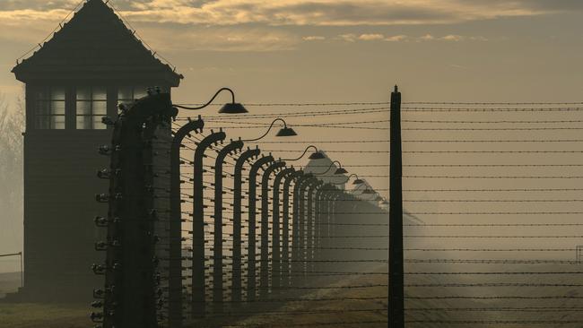 The sun rises over the barbed wire electrified fence that surrounds the Auschwitz II-Birkenau extermination camp. Picture: Getty Images.