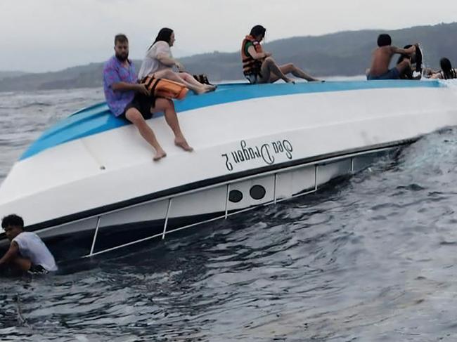 This handout from the Klungkung District Police shows survivors sitting on the hull of the capsized boat. Picture: AFP