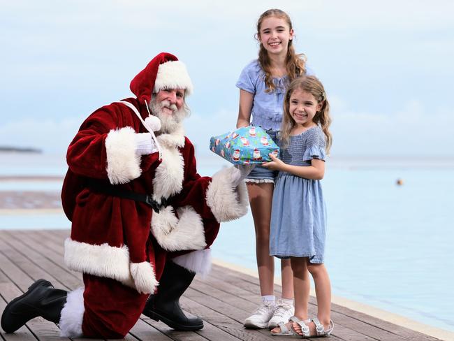 Bruce Skilbeck has been playing Santa Claus at DFO Shopping Centre this year, spreading the joy of the Christmas season to the young and the young at heart. Santa, aka Bruce Skilbeck, gifts a Christmas present to his grand daughters Lilly Hogan, 11, and Grace Hogan, 5, at the Esplanade Lagoon. Picture: Brendan Radke