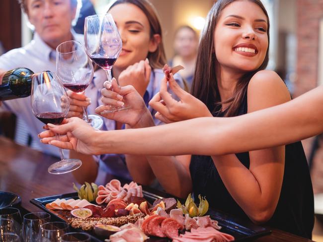 Happy young women at the bar counter having red wine and delicatessen appetizers