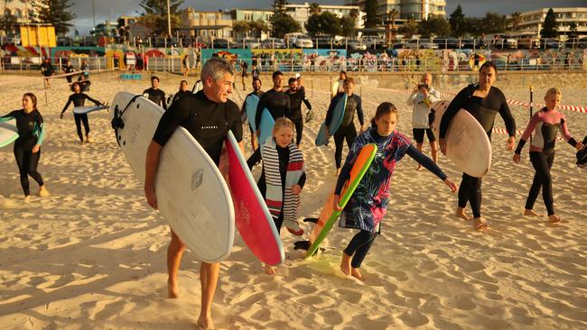 Frida Haggstrom, 10, and her dad Erik and sister Poppy, 12, were among dozens of surfers who flocked to Bondi as the gates flung open after a four-week lockdown. Picture: Rohan Kelly