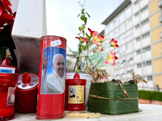 A candle with a picture of Pope Francis is set at the bottom of a statue of Pope John Paul II at the Gemelli hospital where Pope Francis is hospitalised. Picture: AFP