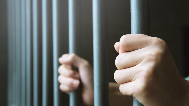 Man in prison hands of behind hold Steel cage jail bars. offender criminal locked in jail.