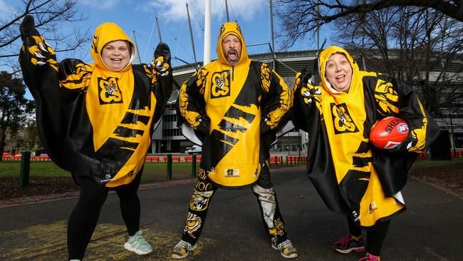 Richmond cheersquad members Melanie Castleman, Paul Clarke and Tonya Baker are ready for this weekend’s rain. Picture: Ian Currie