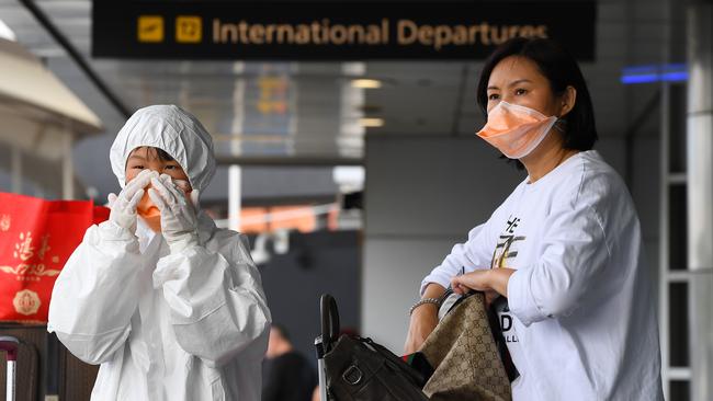 People are seen dressing in personal protective equipment outside the international departures terminal at Tullamarine Airport. Picture: AAP