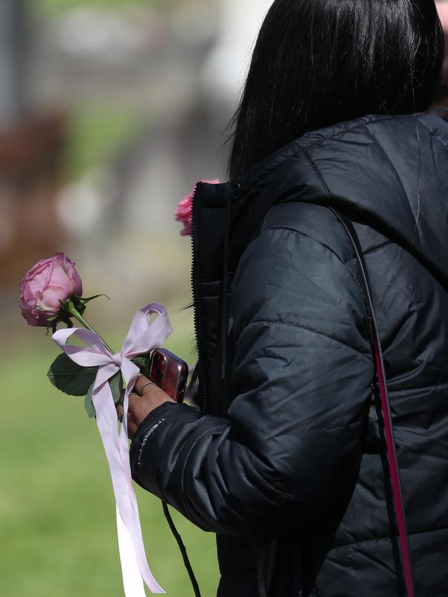 A mourner holds a Pink rose outside Summer William’s funeral. Picture: John Grainger