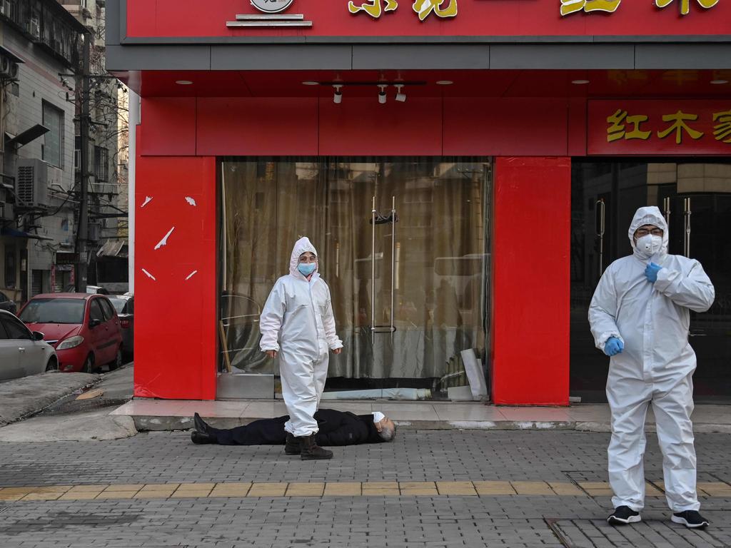 Confronting horror … officials check on an elderly man wearing a face mask who collapsed and died on a street in Wuhan – an image that became symbolic of the unfolding disaster.