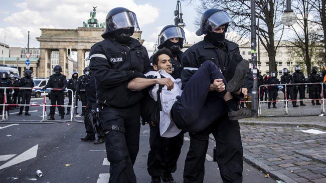 Police arrest a demonstrator during protests against new legislative measures to rein in the coronavirus pandemic next to the Brandenburg Gate in Berlin, Germany. Picture: Getty Images