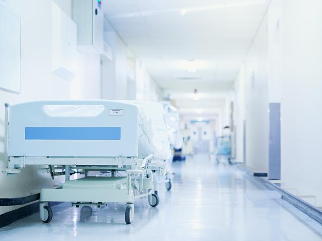 Shot of a hospital bed in an empty corridor of a modern hospital. Photo: iStock