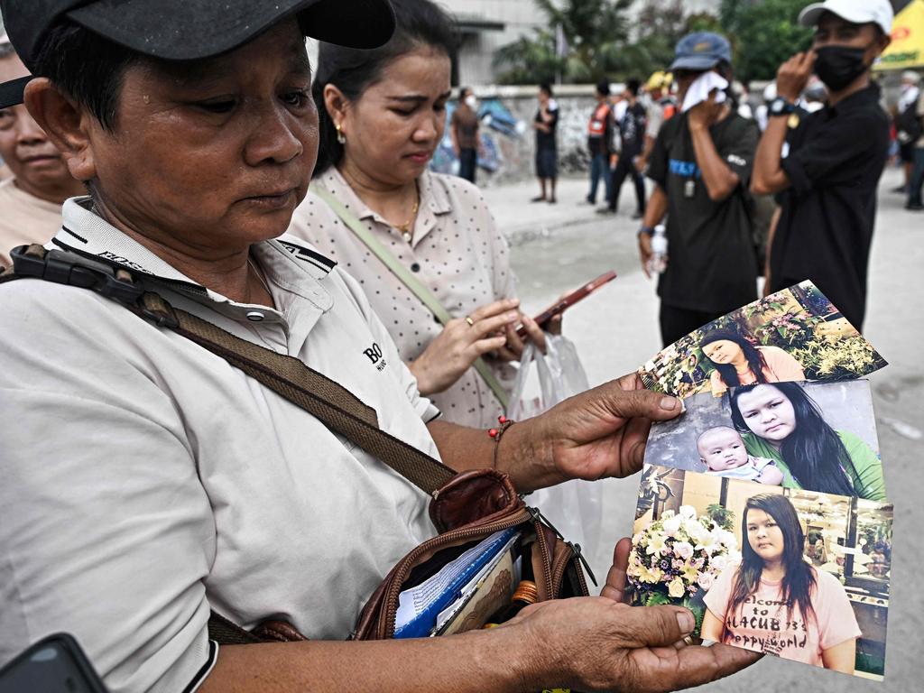 Wassana Phromma (L), from Thailand's northeastern province of Khon Kaen, shows photographs of her missing daughter Anusara, 35, at the site of an under-construction building collapse in Bangkok. Picture: Lillian Suwanrumpha/AFP