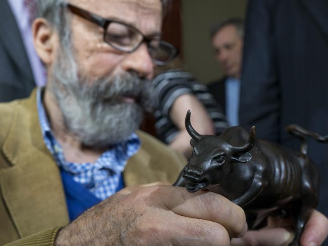 Sculptor Arturo Di Modica holds a model of Charging Bull, the depiction of the full size piece he created that draws thousands of visitors in lower Manhattan, during a news conference Wed., April 12, 2017, in New York. Di Modica and his attorneys announced at the news conference that he's challenging city officials who issued a permit for "Fearless Girl," a bronze statue that faces the bull sculpture on the same cobble stone island in the street, and has drawn worldwide attention. (AP Photo/Craig Ruttle)