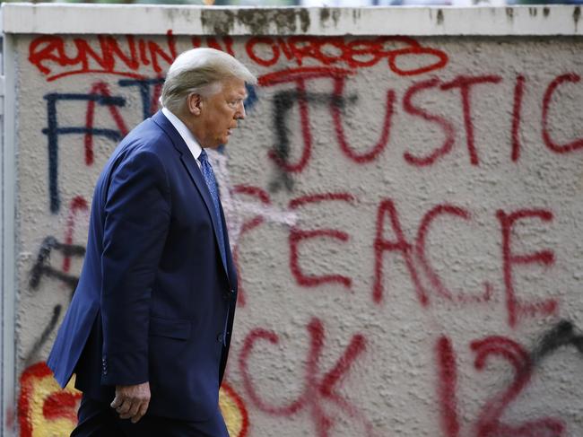 President Donald Trump walks from the White House past graffiti in Lafayette Park to visit St. John's Church in Washington on Monday, June 1, 2020. (AP Photo/Patrick Semansky)