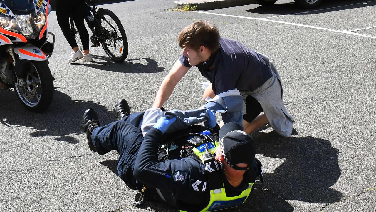 A man tries to avoid being arrested by police at Melbourne's Queen Victoria Market. Picture: William West/AFP