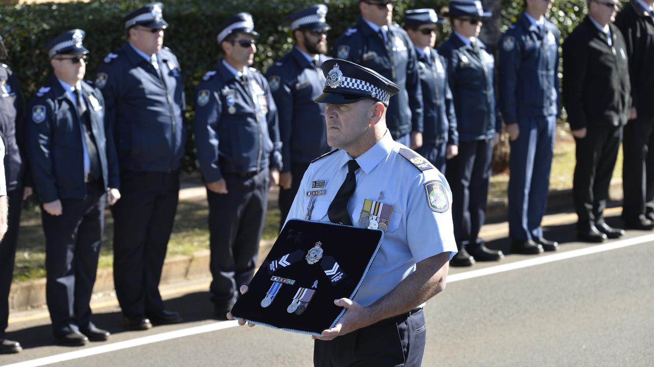 Senior Sergeant Scott Stahlhut carries a cushion with Senior Constable Brett Forte citations and medals through the guard of honour following the fatal ambush.