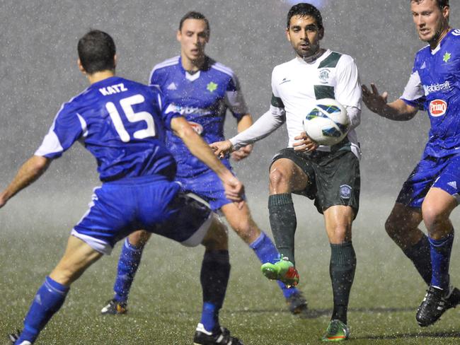 Hakoah players swarm a Northern Tigers player in torrential rain at Hensley Athletic Field.