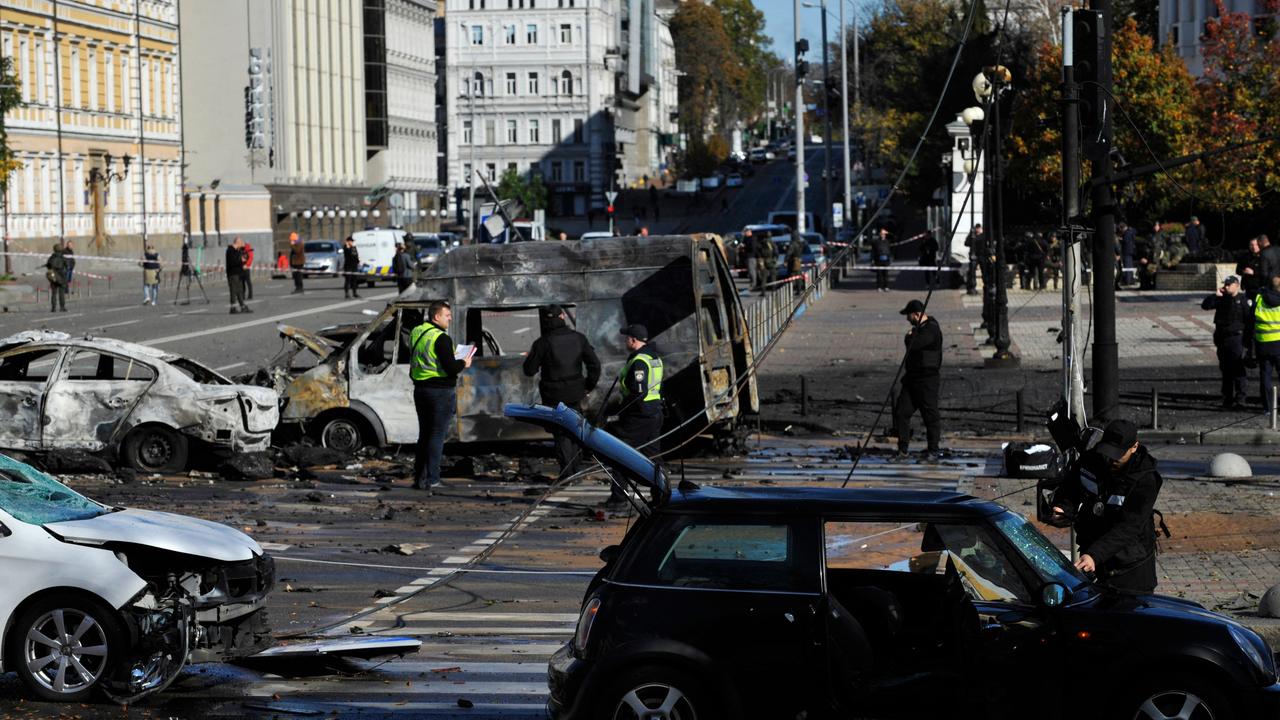 Police experts examine destroyed vehicles in the centre of Kyiv after a missile strike (Photo by SERGEI CHUZAVKOV / AFP)