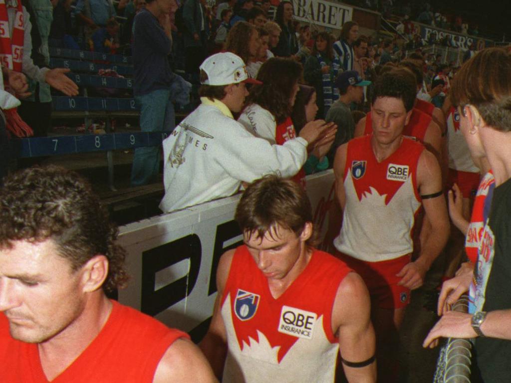 The dejected Swans leave Princes Park after going down to North Melbourne by 127 points under caretaker coach Brett Scott.