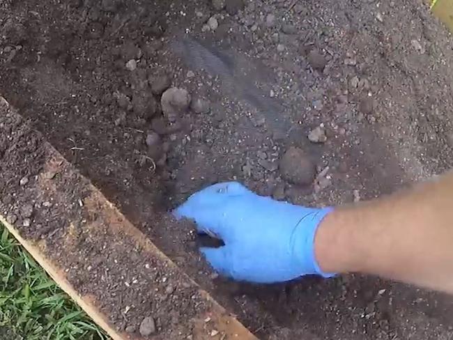 Officers dig through the garden of one of the properties to locate a secret stash of drugs as part of a major police operation.