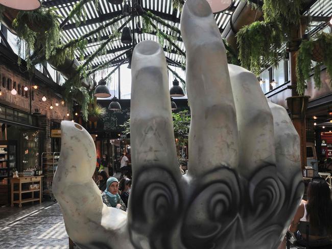 People eat next to a giant sculpture of a hand, at a food court in Israel's Mediterranean coastal city of Tel Aviv as Covid cases continue to rise.