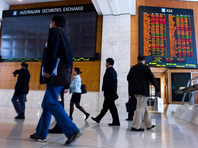 People walk in front of an electronic board which displays stock prices inside the Australia Securities Exchange (ASX Ltd.), building in Sydney, Australia, on Monday, Nov. 1, 2010. Singapore Exchange Ltd.'s A$8.1 billion ($8 billion) bid for ASX Ltd. will be vetted by Australia's Foreign Investment Review Board before approval, Prime Minister Julia Gillard said in an interview with the Australian Broadcasting Corp. Photographer: Ian Waldie/Bloomberg